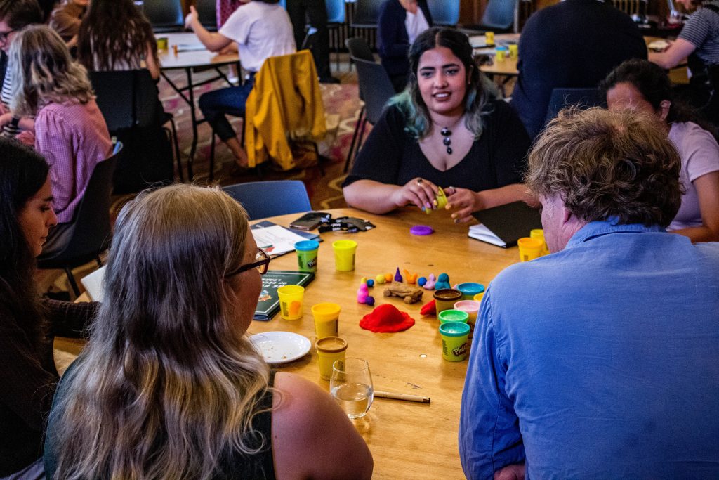 Students and staff building a model of student-staff partnership in play-doh and discussing it. 